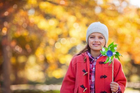 Happy Child with Pinwheel in Autumn Park