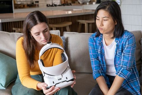 Women exploring virtual reality headset in modern living room