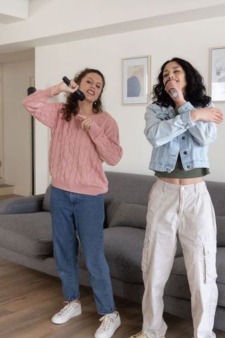 Friends singing karaoke at home performing duet in cozy living room with casual style