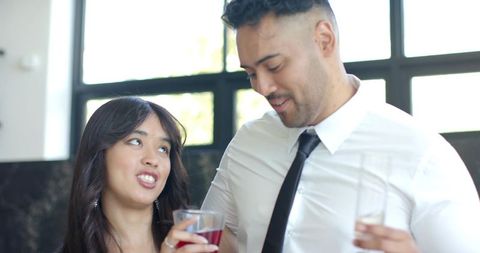 Couple enjoying drinks and conversation by black-framed windows in modern daylight lounge