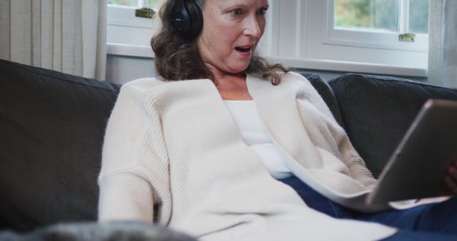 Middle-aged woman wearing headphones, reacting to tablet content - Download Free Stock Images Pikwizard.com