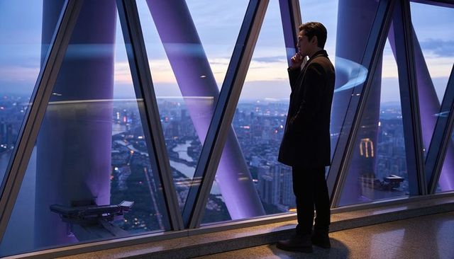 Businessman standing by purple-lit tower supports overlooking river skyline at twilight