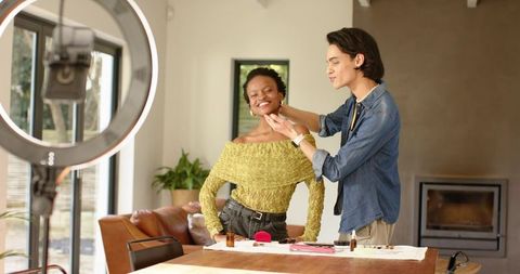 Makeup artist contouring model during at-home beauty tutorial with ring light and brushes