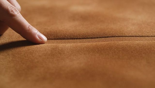 Finger tracing suede seam warm brown cushion macro texture for upholstery detail