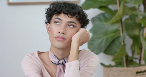 Contemplative person relaxing indoors with greenery background
