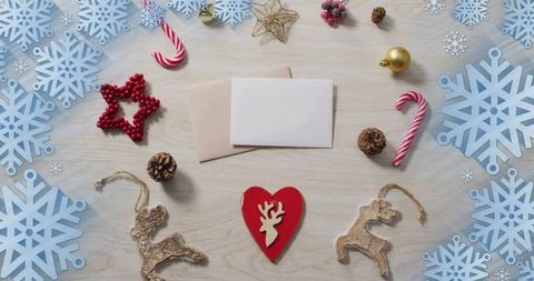 Red heart reindeer ornament resting on light wood with envelopes and winter decorations