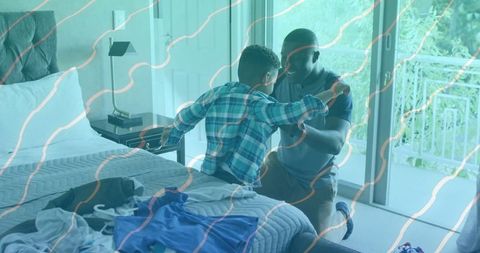 Father bonding with son in bedroom by glass door