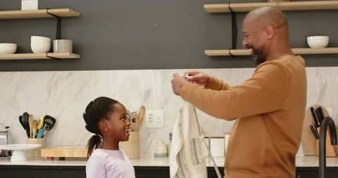 Father and Daughter Bonding in Kitchen Unfolding Dish Towel