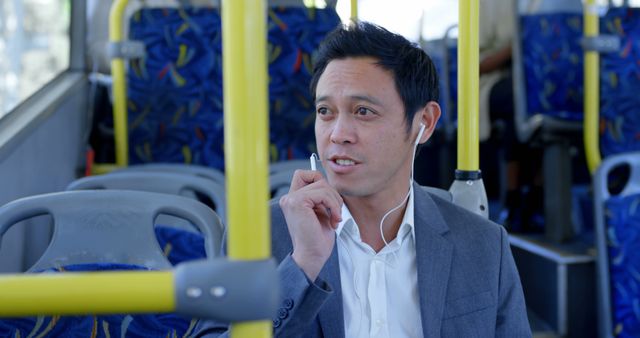 Biracial man sitting in city bus using earphones. Communication, transport, city living and lifestyle, unaltered.