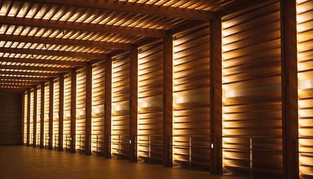 Glowing wooden slatted corridor with repeating beams, amber backlight and deep perspective