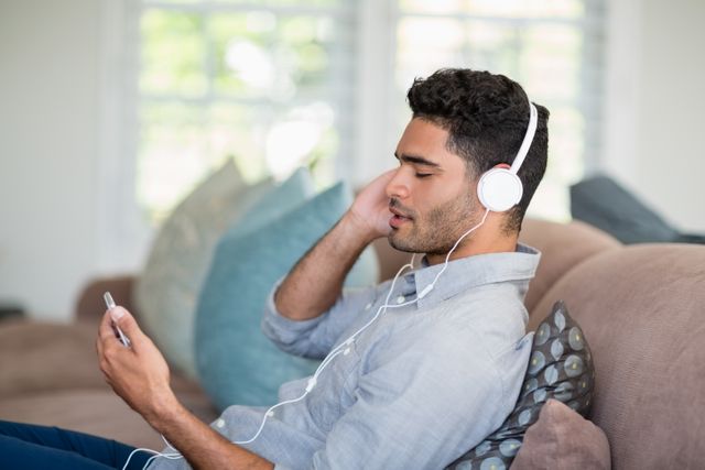 Man listening to music on mobile phone in living room - Download Free Stock Photos Pikwizard.com