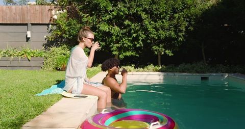 Couple Relaxing by Poolside Drinking Beverages Under Bright Sunlight