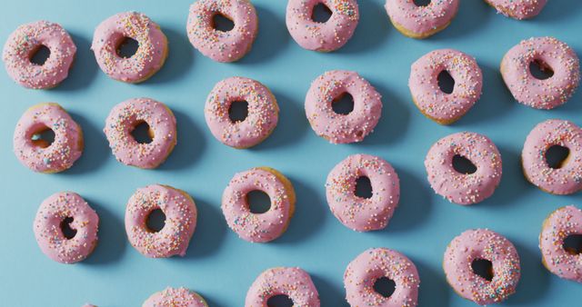 Rows of Pink Iced Donuts with Sprinkles on Blue Background - Download Free Stock Images Pikwizard.com