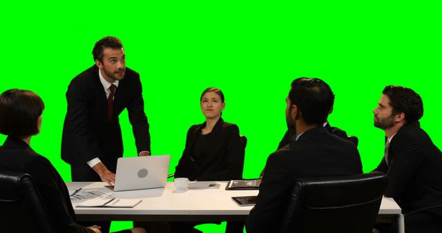 Businessman touching invisible screen while using laptop against green screen
