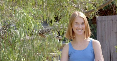 Young Woman Relaxing in Serene Backyard Garden with Willow Tree