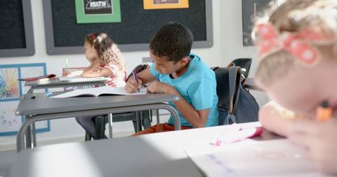 Diverse students concentrating on schoolwork in bright classroom