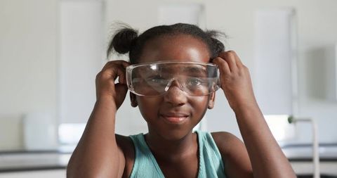 Young student wearing safety goggles in school science lab showing curiosity and focus