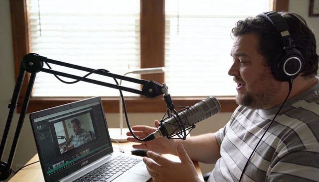 Home podcaster recording on laptop with professional microphone and headphones for content