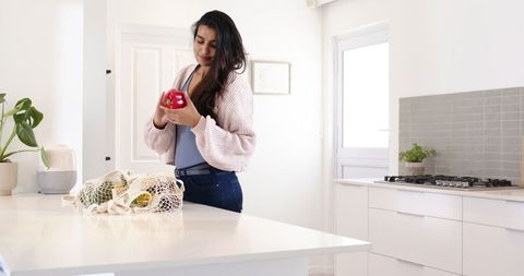 Woman inspecting red bell pepper in modern minimalist kitchen