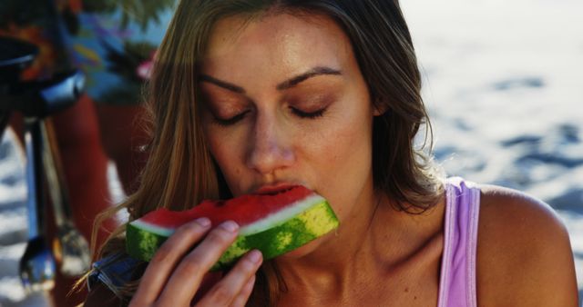 Happy caucasian woman eating watermelon in the sun at beach. Free time, summer and vacations, unaltered.