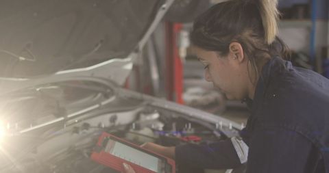 Female Mechanic with Diagnostic Tool Inspecting Car Engine