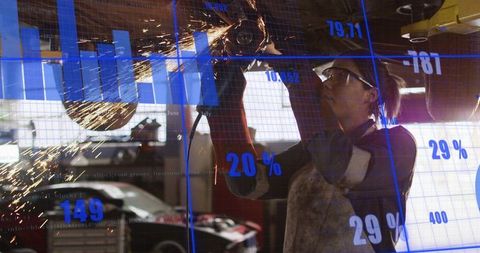 Female Metalworker Grinding Overhead Car Part Wearing Goggles, Sparks Flying with Data Overlay