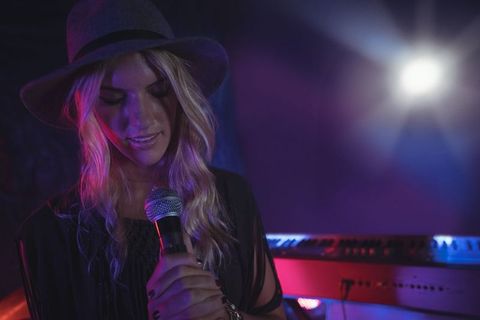 Blonde Female Singer Illuminated on Stage with Microphone - Download Free Stock Images Pikwizard.com