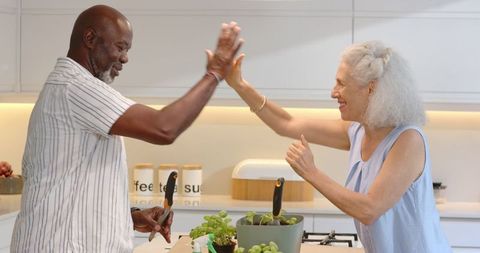 Senior Couple Gardening Enthusiasts High-Fiving Over Kitchen Herbs
