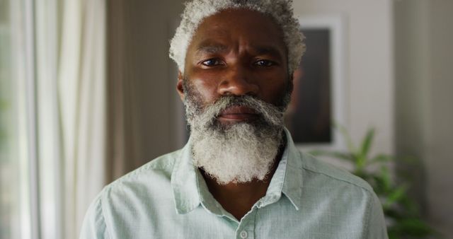 Portrait of african american senior man with beard looking to camera and smiling. staying at home in isolation during quarantine lockdown.