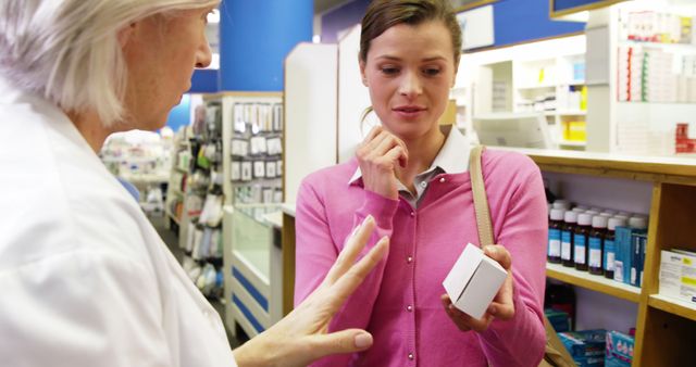Woman consulting experienced pharmacist in drugstore about medication. Image can be used for healthcare services, informational materials about pharmacy consultations, or retail environment advertisements in pharmacies.