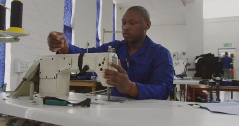 Man operating industrial sewing machine in textile workshop
