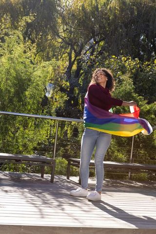 Joyful Celebration with Pride Flag on Sunny Wooden Deck