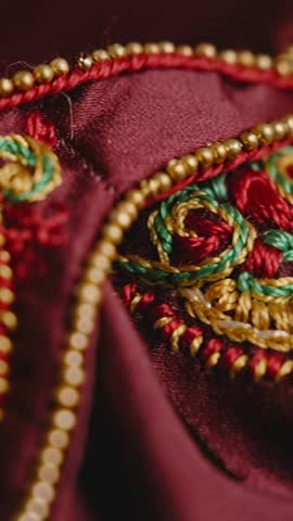 Sliding camera over embroidered textile with gold bead trim and colorful threadwork