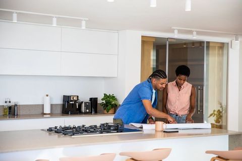 Diverse Couple Consulting Renovation Plans in Modern Kitchen