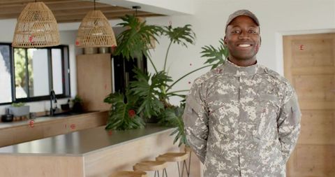 Smiling soldier standing at modern kitchen island with greenery and open-plan interior