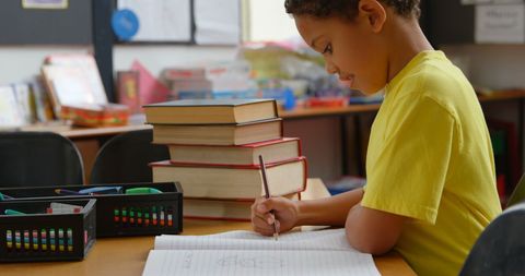 African American Schoolboy Studying in Classroom Writing in Notebook