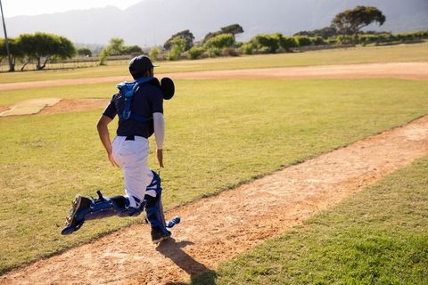 Teen baseball catcher sprinting on field during game