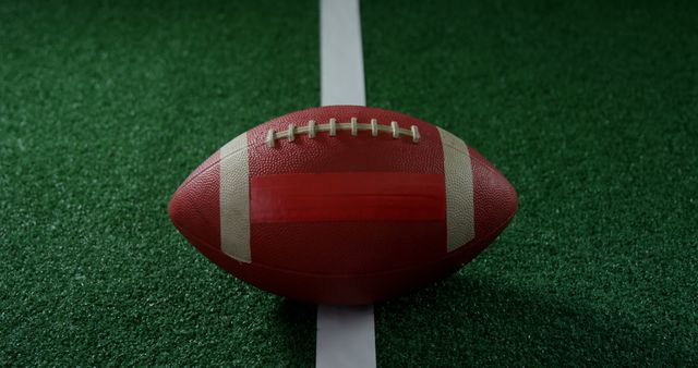 Close-up of American football resting on turf field, showing white yard line. Suitable for football game promotions, sports equipment ads, or articles about American football. Highlights football culture and game strategy.