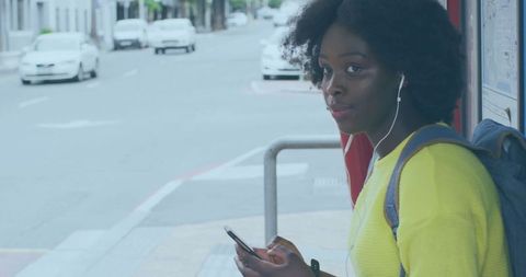 Woman waiting at bus stop engaging with technology