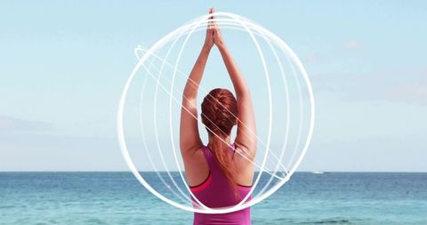 Coastal yoga practice woman stretching in standing prayer pose with light halo rings