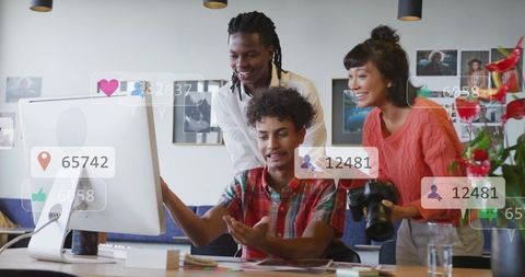 Creative team reacting to social media analytics while collaborating on visual content at desk