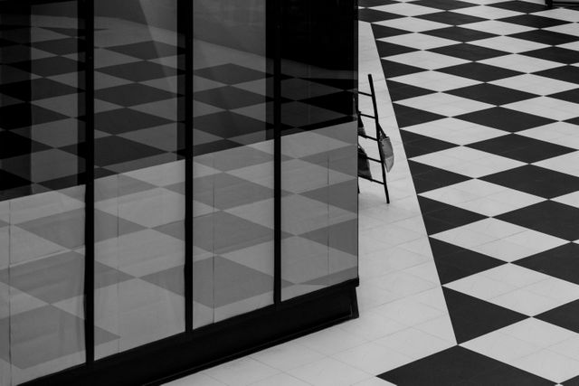 Simplistic and modern design featuring black and white checkerboard floor with reflections on the adjacent wall. Ideal for use in articles about modern architecture, minimalistic design, urban living spaces, and contemporary office settings. Suitable for backgrounds in design applications or conveying themes of symmetry and order.