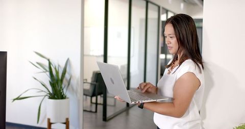 Professional Woman Engaging with Laptop in Modern Office Environment