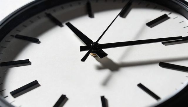 Close-up minimalist analog clock face showing bold shadows and black baton hands on white dial
