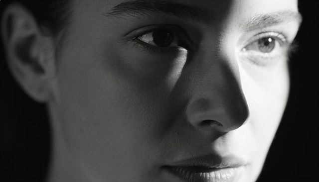 Close-up female face in chiaroscuro lighting showing intense expression, high-contrast