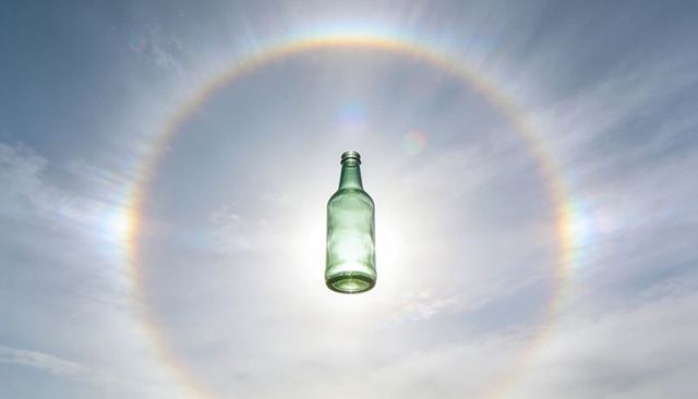 Green Glass Bottle Floating in Sun Halo with Prism Rainbow and Dramatic Lens Flare