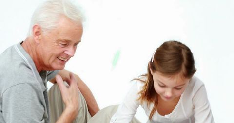 Grandfather Smiling Watching Granddaughter Leaning Forward During Playful Bonding Moment