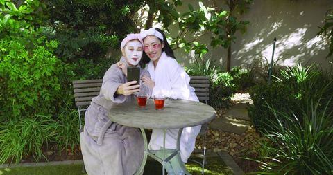 Mother and daughter relaxing with skincare on patio