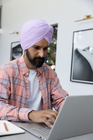 Indian professional man in turban working on laptop at home office