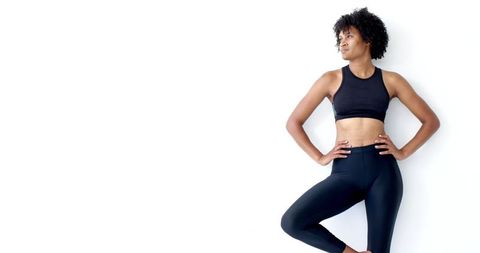 Athletic Woman Leaning Against White Wall in Activewear
